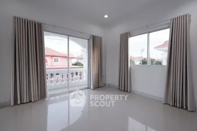 Spacious empty room with large windows and elegant curtains, offering a bright and airy atmosphere.