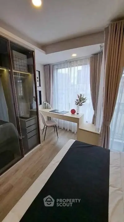 Modern bedroom with stylish decor, large window, and cozy workspace in a contemporary apartment.