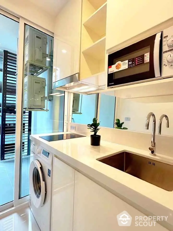 Modern kitchen with sleek appliances and washing machine in compact layout