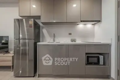 Modern kitchen with sleek cabinetry, stainless steel fridge, and built-in microwave in a stylish apartment.