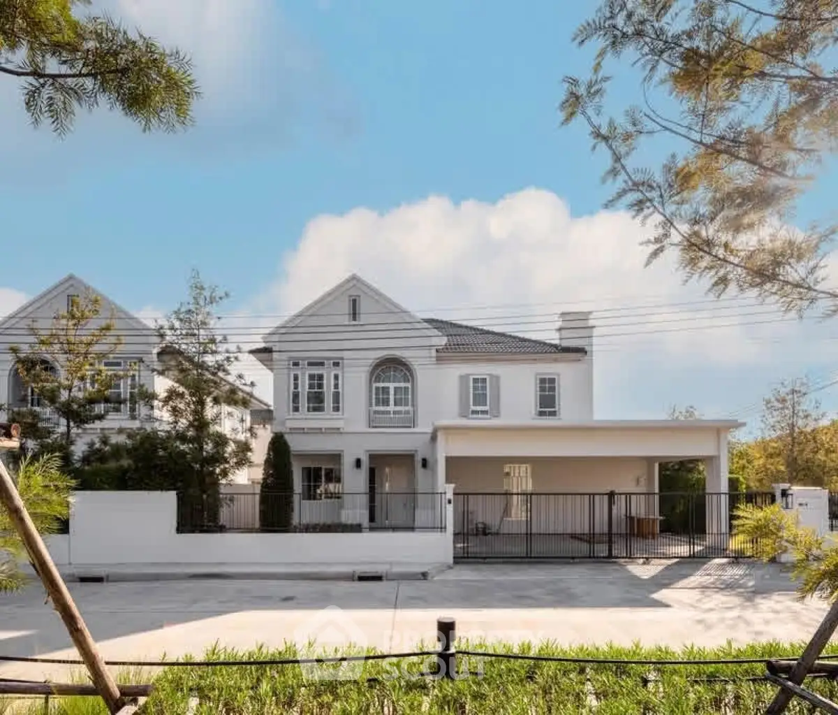 Elegant white two-story house with spacious driveway and lush greenery.