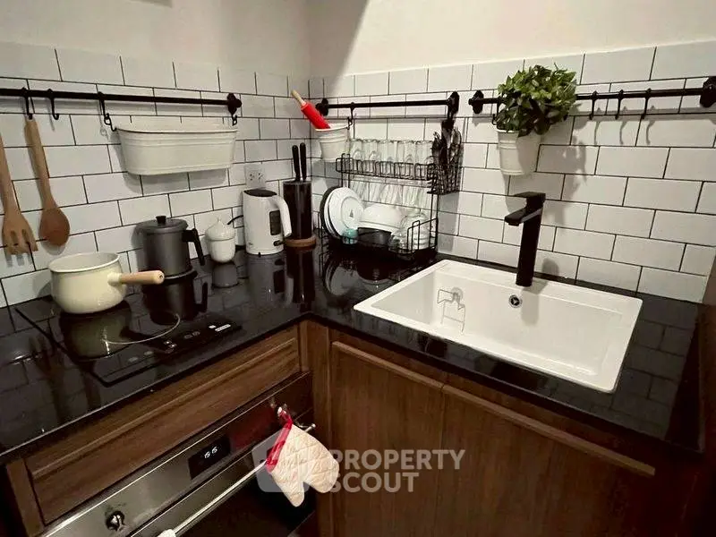 Modern kitchen with sleek black countertop and white subway tiles.