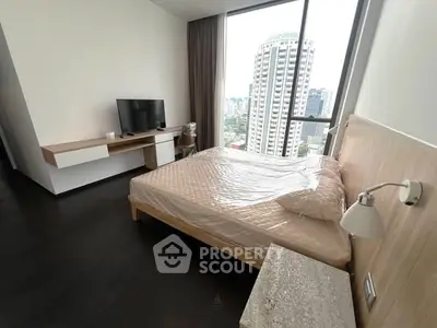 Modern bedroom with city view, featuring sleek furniture and large windows for natural light.