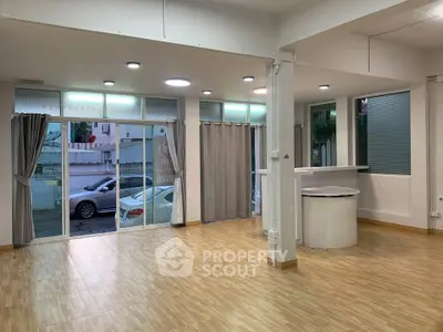 Spacious open-plan room with large windows and wooden flooring, ideal for versatile use.