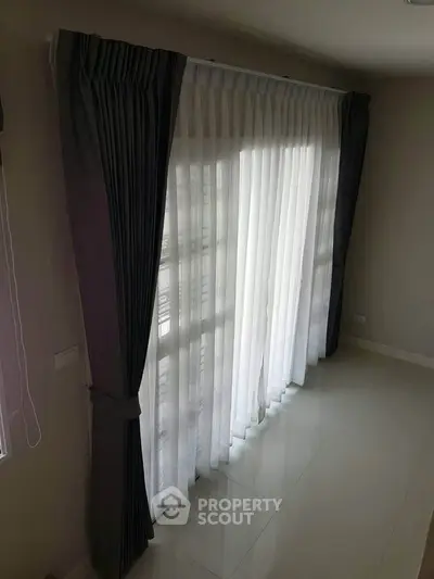 Spacious room with elegant floor-to-ceiling curtains and natural light