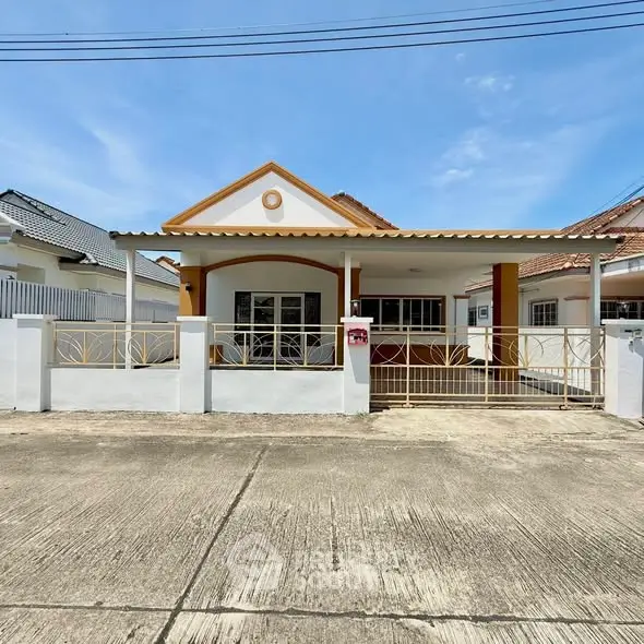 Charming single-story house with gated entrance and spacious driveway under clear blue skies.