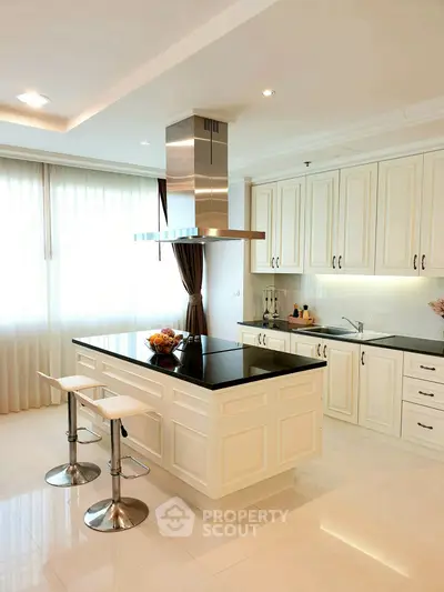 Luxurious modern kitchen with island and sleek cabinetry in bright, airy space.