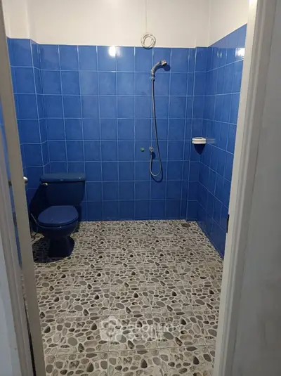 Spacious blue-tiled bathroom with shower and modern fixtures.