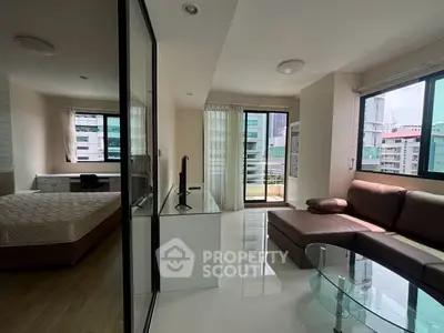 Modern open-plan living room with glass partition and city view, featuring sleek furniture and natural light.