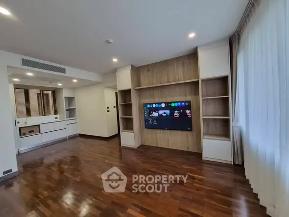 Spacious modern living room with wooden flooring and built-in entertainment center.