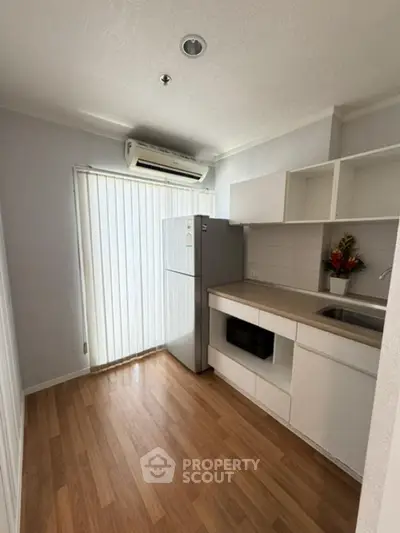 Modern kitchen with wooden flooring and sleek white cabinets