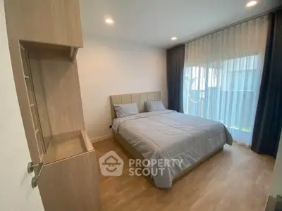 Modern bedroom with wooden flooring and large window for natural light