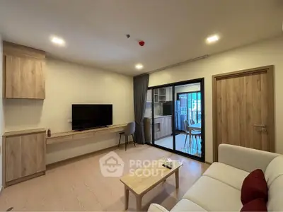Modern living room with wooden flooring, cozy sofa, and wall-mounted TV, leading to a bright balcony.