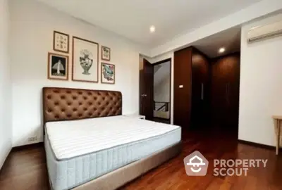 Spacious bedroom with elegant decor and wooden flooring, featuring a stylish bed and ample closet space.