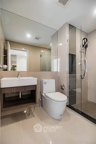 Modern bathroom with glass shower and sleek fixtures in contemporary apartment.