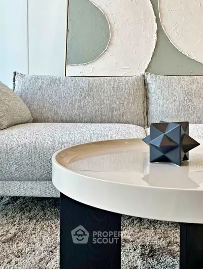 Modern living room with stylish sofa and geometric decor on sleek coffee table.