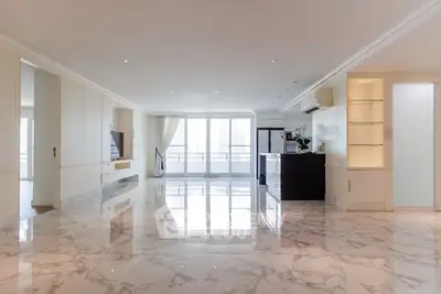 Spacious modern living room with marble flooring and large windows offering natural light.
