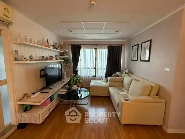 Cozy living room with modern decor, wooden flooring, and natural light from large window.