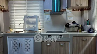 Modern kitchen with sleek cabinets and electric stove, featuring a cozy and functional design.