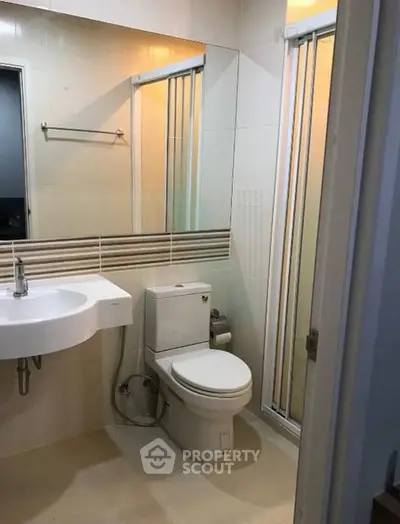 Modern bathroom with sleek fixtures and a compact design, featuring a shower and contemporary sink.