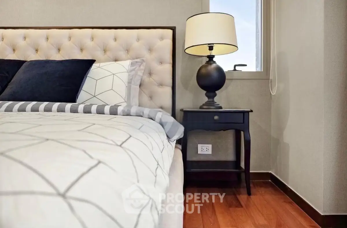 Elegant bedroom with plush bed and stylish lamp on wooden floor
