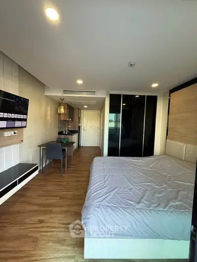 Modern studio apartment with sleek design and open layout, featuring a cozy bed and compact kitchen area.