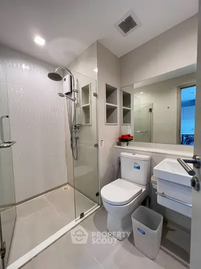 Modern bathroom with glass shower, sleek fixtures, and elegant tile design.
