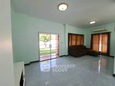 Spacious living room with large windows and garden view, featuring modern sofa and air conditioning.