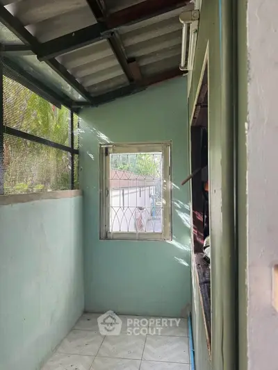 Cozy enclosed balcony with natural light and garden view, perfect for relaxation or small storage space.