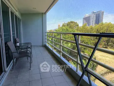 Spacious balcony with outdoor seating and scenic view of greenery and city skyline.