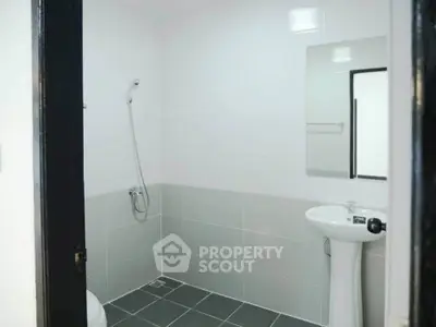 Modern minimalist bathroom with sleek white and gray tiles and a pedestal sink.