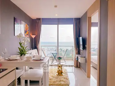 Modern living room with ocean view, stylish decor, and cozy dining area in a high-rise apartment.