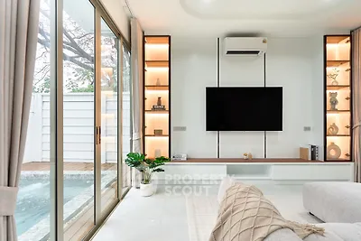 Luxurious living room with pool view, modern decor, and large TV setup