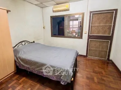 Cozy bedroom with wooden flooring and air conditioning in a residential property.