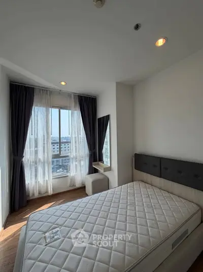 Bright bedroom with large window and modern decor, perfect for urban living.