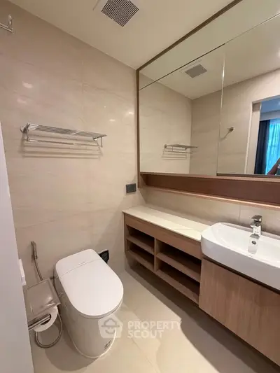 Modern bathroom with sleek fixtures and large mirror in a contemporary home.