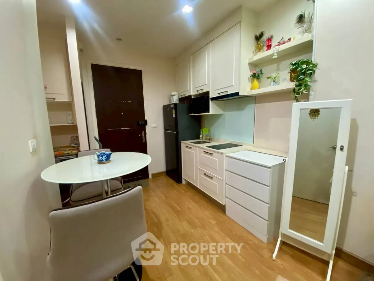 Cozy kitchen with dining area in modern apartment, featuring sleek cabinetry and compact design.