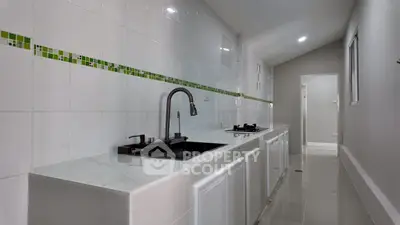 Sleek modern kitchen with white cabinetry and green tile accents