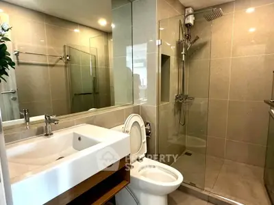 Modern bathroom with glass shower and sleek fixtures in contemporary apartment.