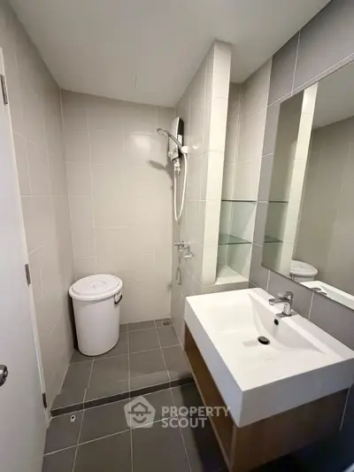Modern bathroom with sleek fixtures and minimalist design, featuring a spacious shower area and stylish sink.