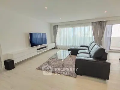 Spacious modern living room with sleek black leather sofa and large TV, perfect for relaxation.