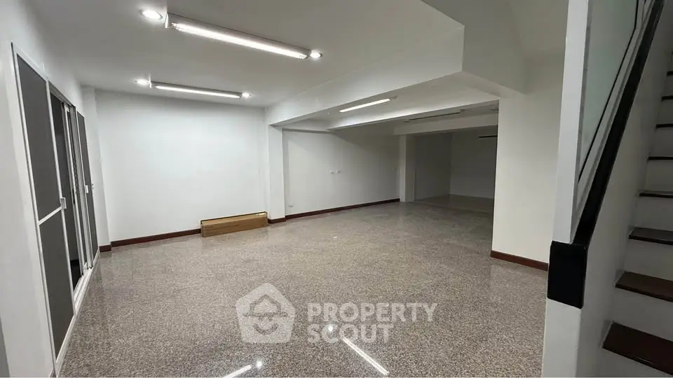 Spacious open-plan interior with modern lighting and staircase, ideal for versatile living or office space.