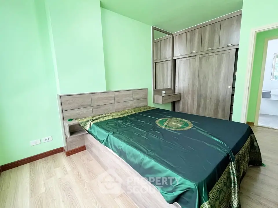 Spacious bedroom with modern wooden furniture and green accents, perfect for relaxation.
