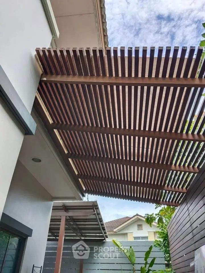 Modern house exterior with stylish wooden pergola and lush greenery