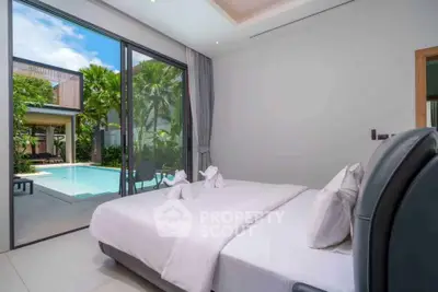 Luxurious bedroom with pool view in modern villa, featuring elegant decor and large glass doors opening to lush garden.