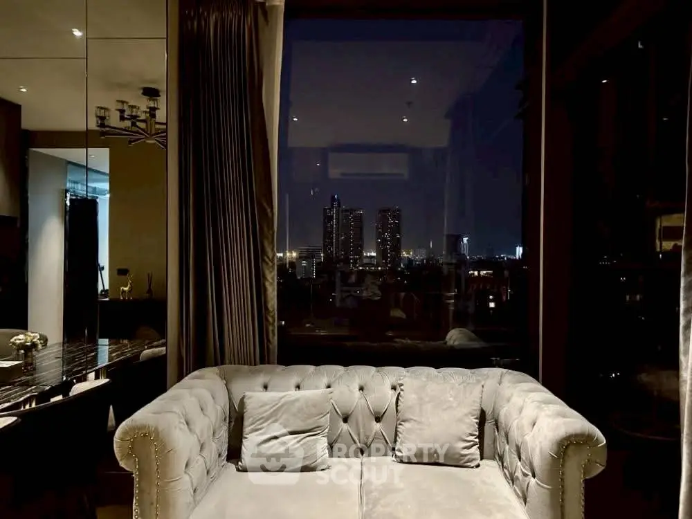 Luxurious living room with plush sofa and stunning city night view through large window.