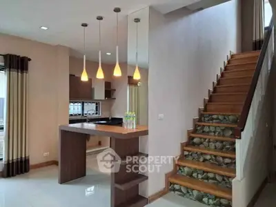 Modern kitchen with stylish lighting and wooden staircase in open layout home