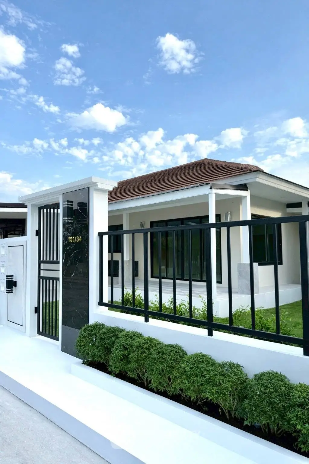 Charming modern house with sleek design and lush greenery under a clear blue sky.