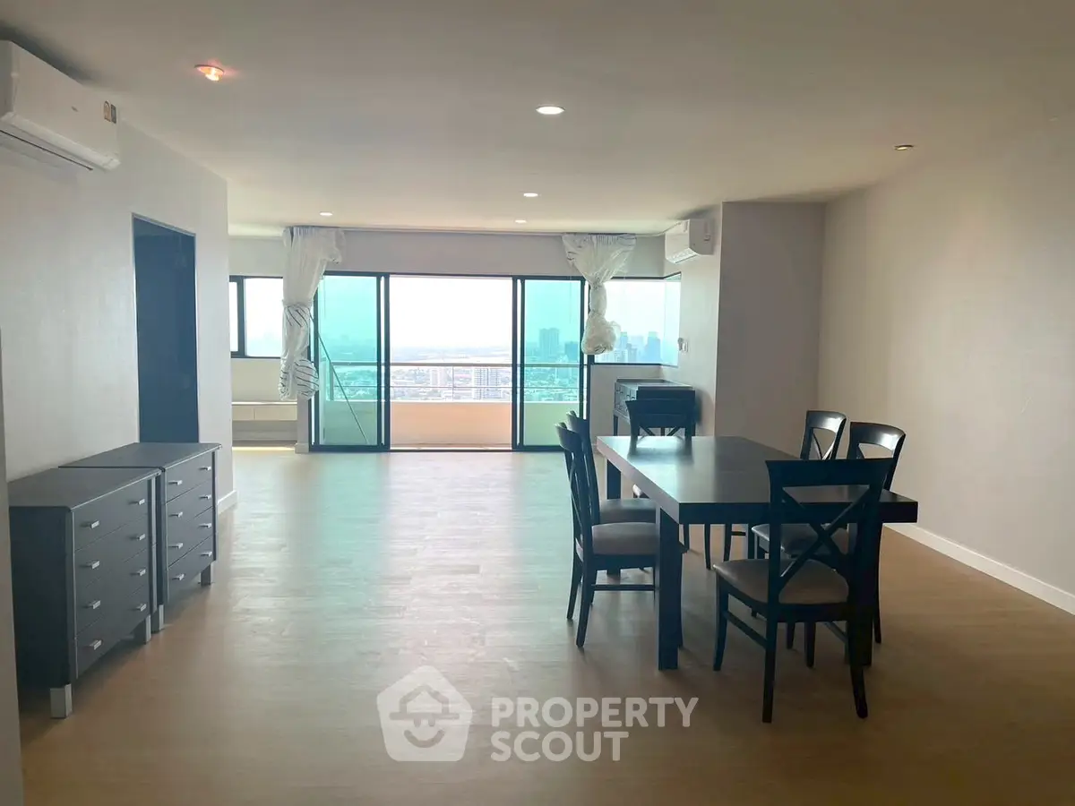 Spacious open-plan living and dining area with city view and large balcony access.
