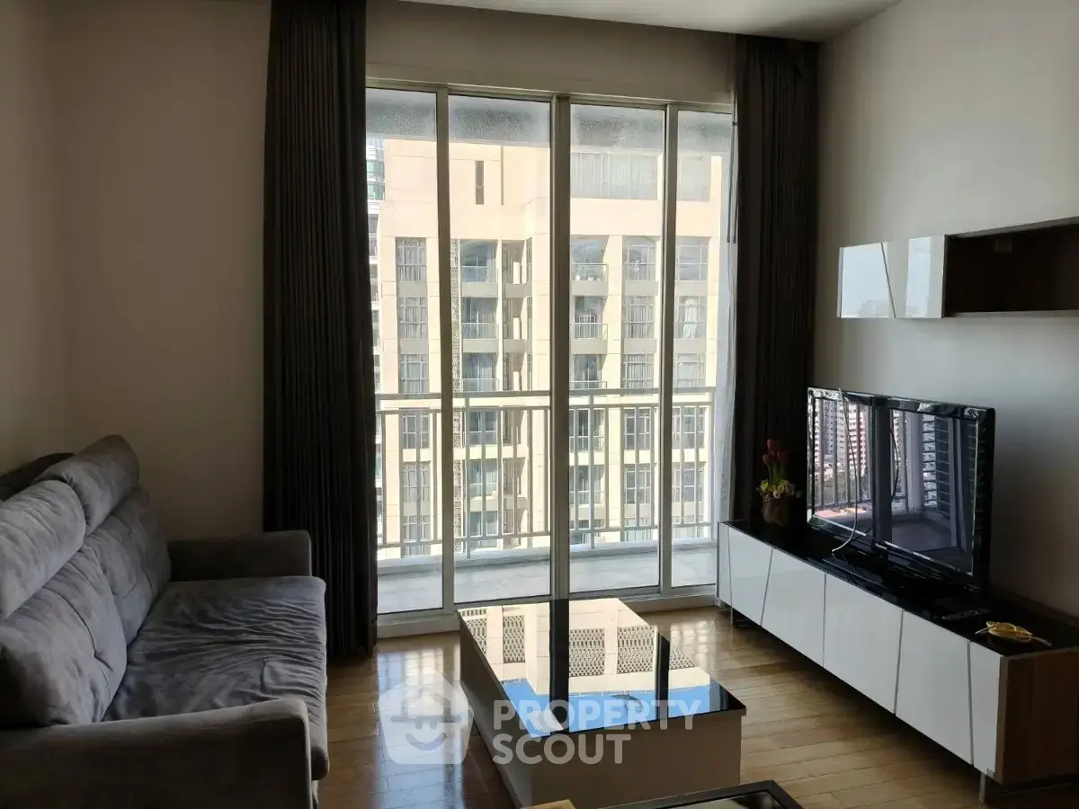 Modern living room with large windows and city view, featuring a cozy sofa and sleek TV stand.